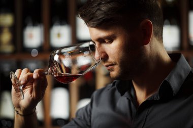 Sommelier, Bokal 'ın arka planında şarap ve mahzende şişe kokusu alıyor. Erkek, renkleri, kaliteyi ve içki tortularını takdir eder. Şarap yapımında profesyonel degustation uzmanı.
