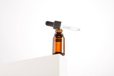 Pipetli siyah başlık açık kahverengi cam üzerinde duruyor. Tıbbi, kozmetik veya kimya endüstrisi için küçük bir şişe. Kehribar şişesi, kap, güzellik ürünü ambalajı, şeffaf sıvıyla birlikte. Metin için yer.