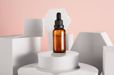 Düşürme kabındaki yumuşak pembe arka planda güzellik ürünleri için soyut tasarım şablonu. Geometrik beyaz şekillerle çevrili cam gibi küçük kozmetik şişeler. Aroma yağı, serum damlası şişesi, flakon