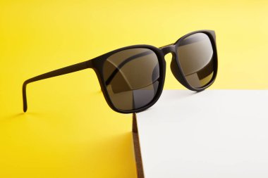 Güneş gözlüğü satışı, katalog sayfası şablonu. Yaz modası aksesuarları sarı arka planda beyaz kaidede. Üst Manzara. Erkek ya da kadın, katlanmış güneşlik, güneş gözlüğü, güneş giysisi, siyah tam kıvrım göz giysisi..