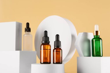 Sarı arka planda cam ambalajlı kadınlar için cilt makyajı. Serumlu damla şişeleri, hyaluronik asit, squalane yağı, beyaz geometrik şekillerde çiçek suyu standı. Katalog düzeni.