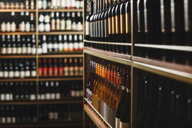 Yakından bakınca mahzendeki ahşap raflarda titizlikle dizilmiş çeşitli şarap şişeleri görülüyor..