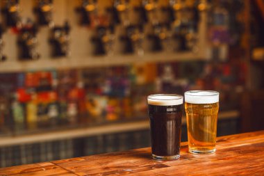 İki farklı bira bardağı, parlak ahşap tezgahın üzerinde dinleniyor.. 