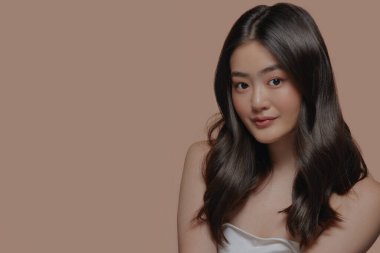 Bej arka planda temiz ve pürüzsüz bir cilde sahip Asyalı güzel bir kadının stüdyo fotoğrafı. Yüz bakımı, yüz bakımı, kozmetoloji, güzellik ve kaplıca, Asyalı kadın portresi.