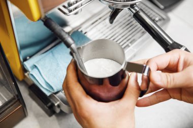 Baristaların elleri, köpüklü dokuya süt dökmek için ustaca çalışan profesyonel kapuçino makineleridir. Kremalı ve kadife kahve ve yakın çekim için çok gereklidir..