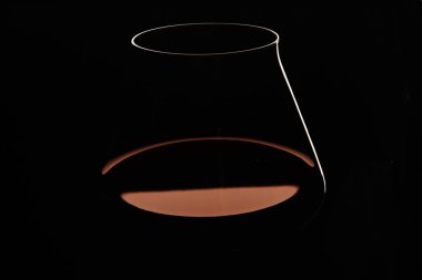 İnce saplı şeffaf cam silueti ve koyu arka planda izole edilmiş kırmızı şarap. Alkol içecek listesi, menü, kart, broşür ve afişin yaratıcı dikey tasarımı. Stüdyo çekimi.