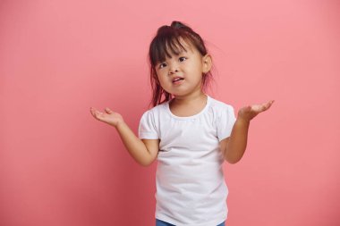 Kafası karışmış küçük Asyalı kız omuzlarını silker ve bir soru ifadesini ifade eder. 