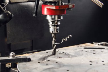 Alt cıvata deliğini deliyorum. Dikey matkapla metal parçalarında delikler açılır. Metal sondaj makinesine yakın çekim.