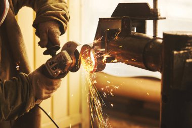 İşçi çeliği öğütücüyle kesiyor, yakın plan. Fabrikadaki metal yapı aracı