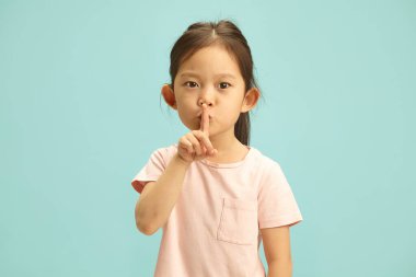 Sessizlik ve sessizlik isteyen, ağzı önünde el kol hareketi yapan, sessiz kalan ya da mavi izole edilmiş arka plana karşı bir sır saklayan ve bedava fotokopi alanı olan küçük tatlı bir çocuk..