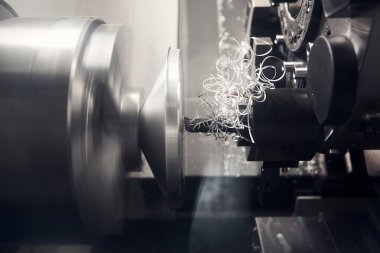 CNC torna makinesi haznesi metal parçaları kesmiş. CNC dönüşüm makinesi tarafından çalışan yüksek teknolojili metal işleme. Bir CNC torna parçalarının yüksek teknoloji üretim süreci, endüstriyel modern