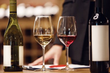 Sommelier eğitimi, şarap okulu. Şarap hazırlama öğretmeni acemi profesyonelleri eğitmeye başladı. İçi kırmızı ve beyaz şarapla dolu şişeler masanın üstünde.