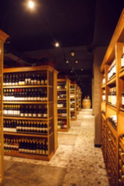 Şarap dükkanındaki büyük mahzendeki geniş açılı ve alkollü içecekler için ahşap raflar. Seçkin alkollü içeceklerle dolu uzun şarap koleksiyonu koridoru. Raflarda çeşitli şişeler var.