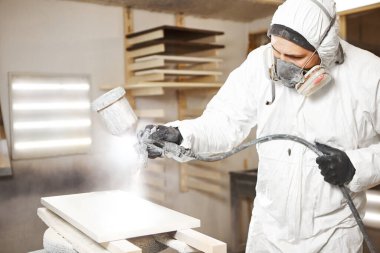 Endüstriyel işçinin boya tabancası veya sprey tabancası kullanarak boya uygulamak için yakın çekim Yangına karşı koruma sağlayan alev geciktirici uygulaması, havasız püskürtme.