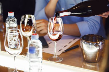 Garson şarap yarışması sırasında şarap kadehlerine kırmızı şarap koyuyor. Alkollü içecekler için şarap garsonu ve personel eğitimi. Profesyonel iş sertifikası sınavı. Şarap.