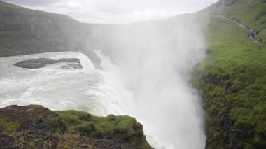 İzlanda 'daki Gullfoss şelalesini yavaş çekim görüntüsü büyük miktarlarda suyun kanyona dalışını gösteriyor. Sis havaya yükseliyor, bu doğal harikanın ham gücünü ve destansı boyutunu ortaya çıkarıyor..