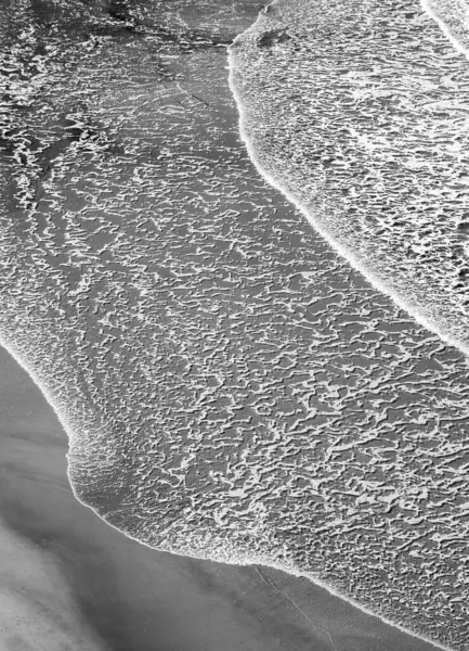 Sanatsal siyah ve beyaz fotoğrafçılıkta yakalanan kumdaki dalgaların dokusu.