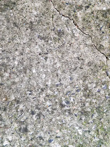 Çatlak ve yosunlu beton kaldırım dokusu doğal kentsel yaşlanma ve yıpranmayı gösteriyor..