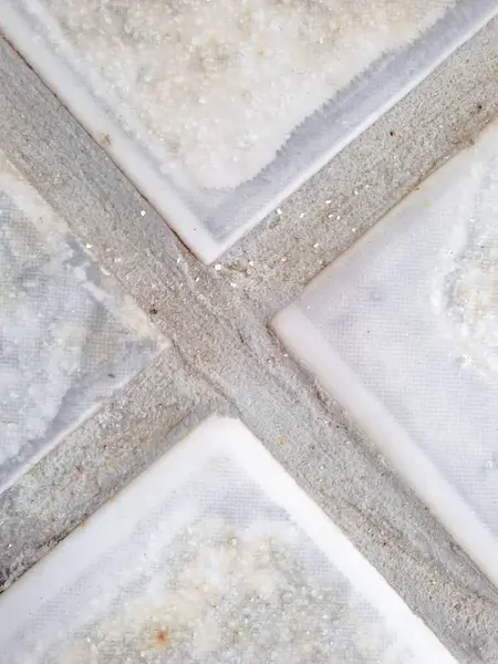 Yakın plan görüntü, dört kayma önleyici karo arasındaki eklemleri gösteriyor, harç hatlarına odaklanıyor ve dış çekiş ve güvenlik için tasarlanmış kaba yüzey.