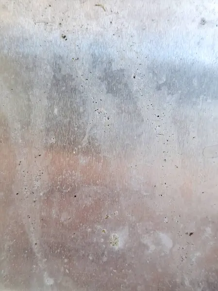 Kullanımdan kaynaklanan aşınma izleri, toprak lekeleri ve doğal kusurları içeren fırçalanmış metal yüzey..
