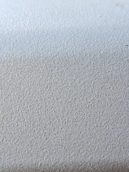 Pürüzsüz ama hafif kumlu bir kaplaması olan beyaz duvar dokusuna yakın çekim, muhtemelen sıva ya da kaygan palto, mat görünümlü..