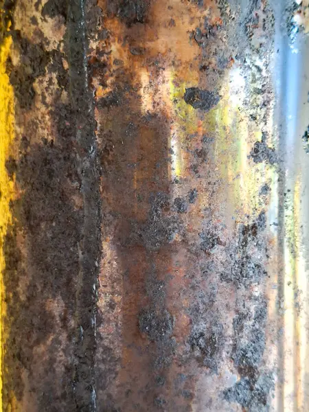 Turuncu, kahverengi ve gri tonlara sahip paslanmış ve soyulmuş bölgeleri olan metal bir yüzeye yakın plan, aşınma detaylarını vurgulamak ve aşınmış boya.