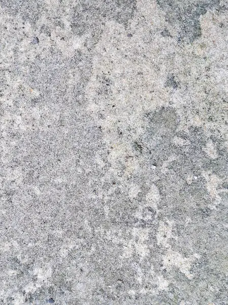 Sert bir yüzeyi ve toprak lekeleri olan beton zemine yakın çekim, kum taneleri, nemden kararmış alanlar ve zamanla aşınan doğal aşınmalar..