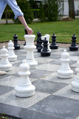 Dişi el büyük bir satranç tahtasında büyük parçaları hareket ettirir.