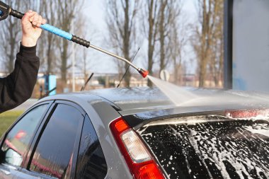 Adam açık havada arabasıyla temas kurmadan araba yıkıyor..