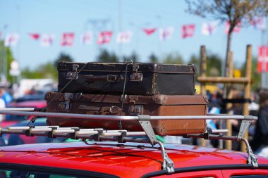 Kahverengi deri eski bavullar en üstteki arabaya yakın.