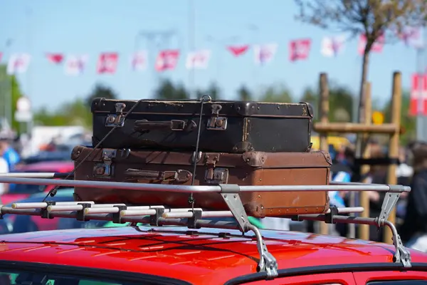 Kahverengi deri eski bavullar en üstteki arabaya yakın.