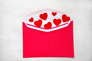 Beyaz zemin üzerinde kalpler olan kırmızı kağıt zarf.