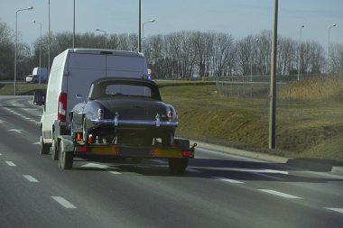 Arabaların taşınması için bir römorkta siyah bir eski arabanın nakliyesi..