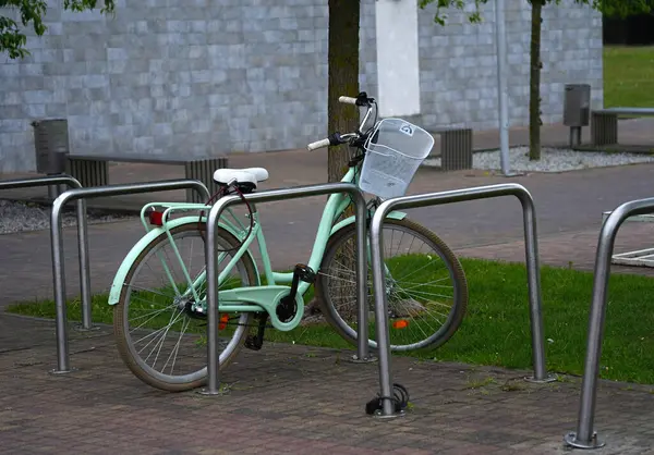 Modern bir kadının nane yeşili bisikleti modern bir duvar binasının arka planına park edilmişti.