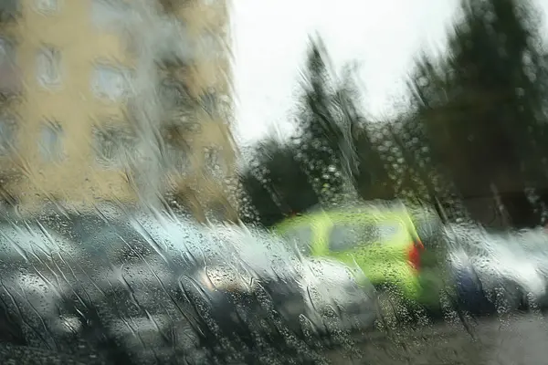 Şehir manzarasının bulanık fotoğrafı bardakta yağmur damlalarıyla birlikte..
