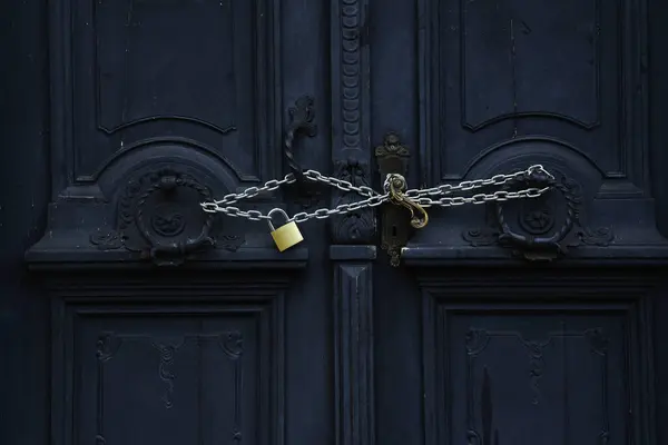 Antika koyu renkli kapı zincirle asma kilitle kapatılmış.