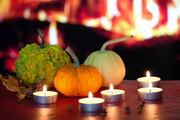 Ateşin arka planında, parlak sonbahar balkabakları ve yanan mumlar
