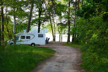 Ormanda yaz manzarası. Park etmiş bir araba. Göl kenarında kamp yapmak için.
