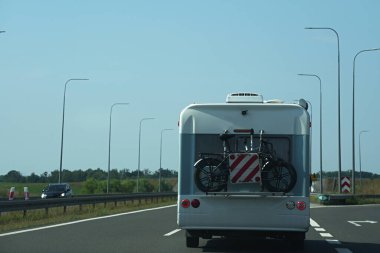 Arkasına bisikleti iliştirilmiş bir karavan. Aşırı yükleme için kırmızı ve beyaz işaretler de görülebiliyor.