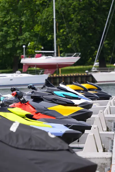 Çok renkli jet skiler ve limana demirlemiş tekneler.