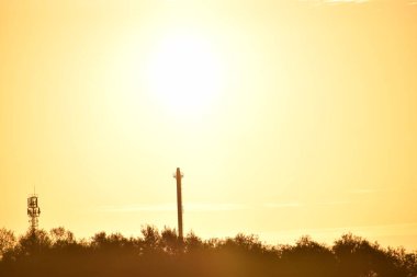 Gün batımının arka planında bir kulenin silueti.
