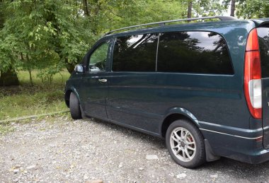 A passenger van is shown stationary in a parking lot, highlighting its compact design and surroundings in natural light