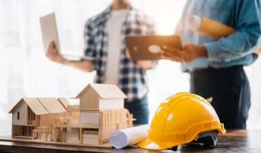 Engineer desk with object paper and tablet with blurry engineer teamwork hardworking to consults about their building project. in office