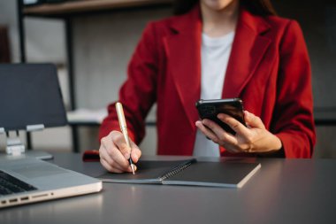 Ofiste bilgisayar, tablet ve akıllı telefon kullanan bir iş kadını. Dijital pazarlama medya mobil uygulaması ve yeni bir başlangıç projesi hakkında tartışmalar. Finans görevi