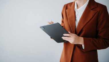 Gülümseyen Kafkasyalı genç iş kadını banka çalışanı yönetici patron kameraya bakıyor, tablet, dizüstü bilgisayar ve not defteri kullanıyor beyaz arka grupta izole edilmiş.
