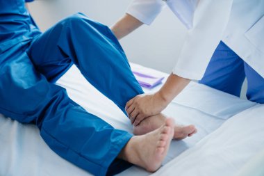 Hastanede ya da klinikte bacağını uzatırken hastaya yardım eden fizyoterapist