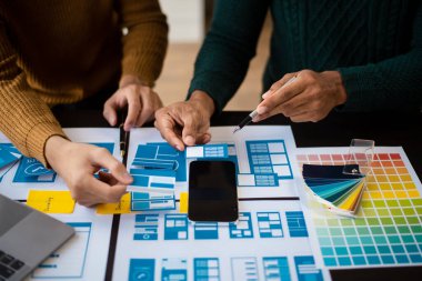  UX geliştiricisi ve ui tasarımcısı ofisteki müşteri breif ve renk kodu ile mobil uygulama arayüzü kablo tasarımı hakkında beyin fırtınası yapıyor.