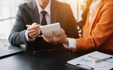 Ofis masasında akıllı telefon ve hesap makinesi olan iş belgeleri dijital tablet ve sosyal ağ diyagramı olan grafik işleri ve ofiste çalışan iki iş arkadaşı