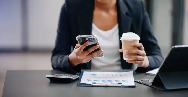 woman using laptop and typing on laptop and holding coffee cup in cafe, home office