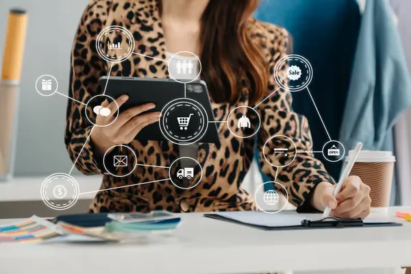  Dizüstü bilgisayar, akıllı telefon ve tablet kullanan ve iş yerindeki internet alışverişinde defter yazan bir kadın eli. Sanal simgeyle evde